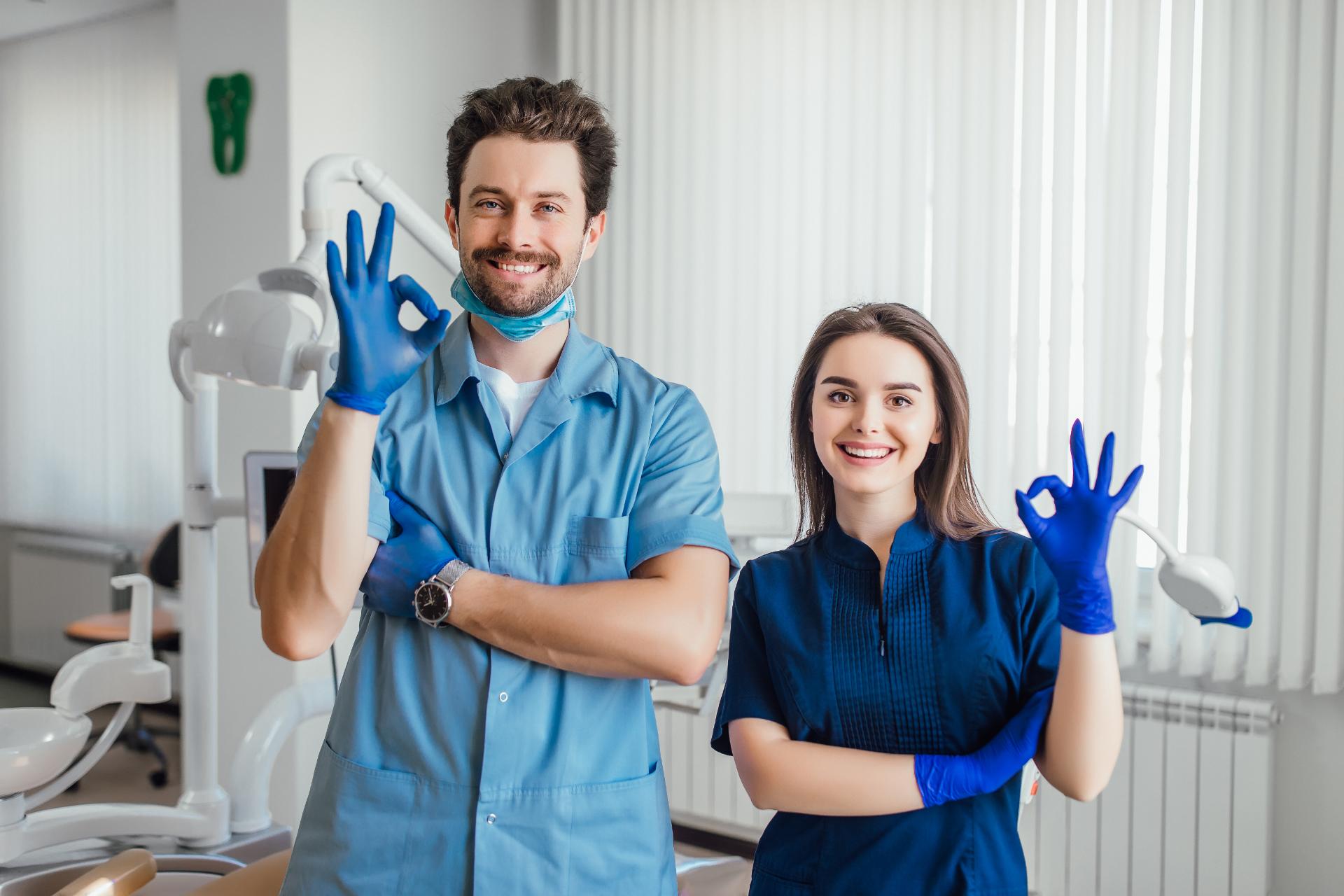 smiling fremont dentist standing with arms crossed with her colleague showing okay sign